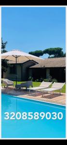 una piscina con due sedie a sdraio e un ombrellone di Villa Bella a Sabaudia