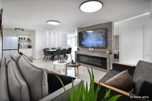 a living room with a couch and a fireplace at אחוזת שקד בוטיק - מתחם פרטי 3 חדרי שינה, בריכה מחוממת , ג'קוזי ונוף בגליל המערבי in ‘Ein Ya‘aqov