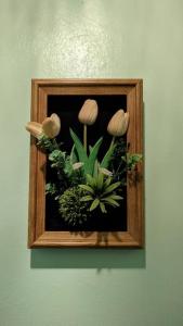 a picture of flowers in a wooden frame on a wall at Didi Lodge - Cabaña cálida y acogedora! in Cañas