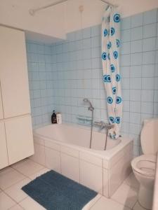 ein Badezimmer mit einer Badewanne, einem WC und einem Duschvorhang in der Unterkunft Chambre 2/4p confortable in Ostende