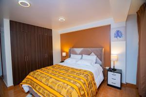 1 dormitorio con 1 cama grande con manta amarilla en Apartahotel KIRI para empresas y familias que viajan en grupo cerca del Aeropuerto Juliaca Perú, en Juliaca