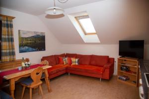 a living room with a red couch and a table at Apartement Seifterhof in Sankt Andrä im Lungau