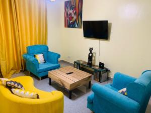 sala de estar con 2 sillas azules y TV en Kigali Center Apartment-1Bedroom, en Kigali