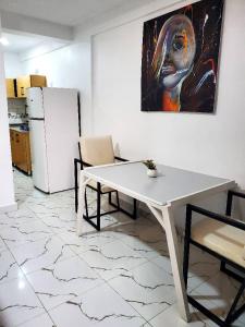 una mesa blanca y sillas en una cocina con una pintura en Kigali Center Apartment-1Bedroom, en Kigali