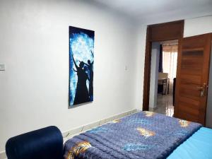 1 dormitorio con 1 cama y una pintura en la pared en Kigali Center Apartment-1Bedroom, en Kigali