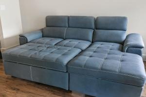 a blue leather couch sitting in a room at Modern Condo with Game Room in Downtown New Orleans in New Orleans