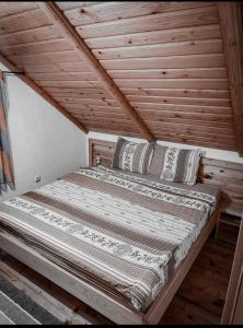 a bed in a room with a wooden ceiling at Chalet Breza in Kolašin