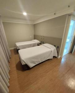 2 Betten in einem kleinen Zimmer mit Holzböden in der Unterkunft Transamerica Executive Bela Cintra (Paulista) in São Paulo