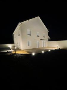 a white house with lights in front of it at night at Maison au sein d’un corps de ferme. 