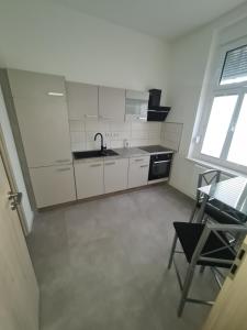 cocina con armarios blancos, fregadero y silla en Apartament Suite 1, en Bernburg