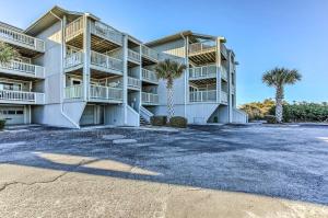 a large apartment building with palm trees in front at Condo with Pool Access - Walk to Beach! in Carolina Beach