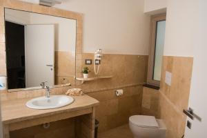 Regia Hotel في Abbasanta: حمام مع حوض ومرحاض ومرآة