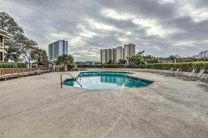 une piscine avec des chaises et des bâtiments en arrière-plan dans l'établissement Myrtle Beach Condo with Pool Less Than half Mi to Beach!, à Myrtle Beach