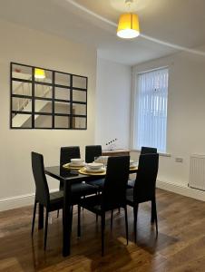 a dining room with a black table and chairs at Large Walton House - EFC & LFC in Liverpool