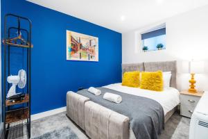 a bedroom with blue walls and a bed with yellow pillows at RIGHT ON - BRIGHTON - By My Getaways in Brighton & Hove