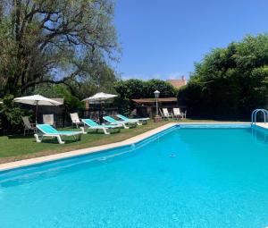 uma grande piscina azul com cadeiras e guarda-sóis em Hostería La Viña em La Cumbre