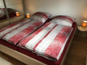 a bed with red and white blankets and pillows on it at Ferienwohnung Kajüte in Wees