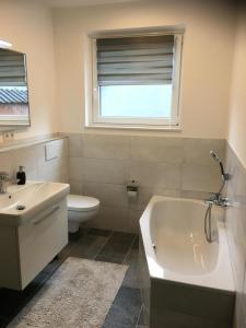 a bathroom with a tub and a toilet and a sink at Ferienwohnung Kajüte in Wees +20 photos