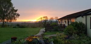 a house with the sunset in the background at The Rock self-catering holiday cottage and garden lodges in Coleford