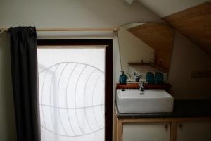 uma casa de banho com um lavatório branco e uma janela em Gîte l'Ecurie em Jodoigne