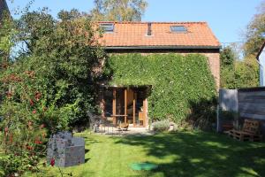 una pequeña casa con un patio cubierto de hiedra verde en Gîte l'Ecurie en Jodoigne