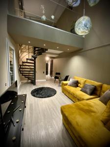 a living room with a yellow couch and a staircase at Cosmopolis Forever Friday Luxury in Ştefăneştii de Jos