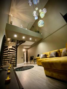 - un salon avec un canapé jaune et un escalier dans l'établissement Cosmopolis Forever Friday Luxury, à Ştefăneştii de Jos