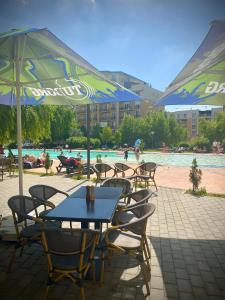 a table and chairs with umbrellas next to a pool at Cosmopolis Forever Friday Luxury in Ştefăneştii de Jos