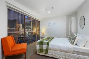 a bedroom with a bed and an orange chair at CBD Stunner - Skytower View - WIFI - Netflix in Auckland