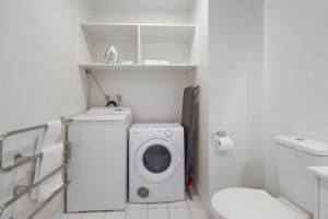 a white bathroom with a washing machine and a toilet at CBD Stunner - Skytower View - WIFI - Netflix in Auckland