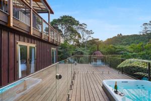 a bath tub sitting on a deck next to a house at Tranquil Sunset Retreat - Spa - WIFI - Netflix in Auckland