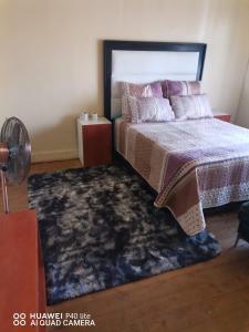 a bedroom with a bed and a rug at New Dawn Guest House in Brakpan