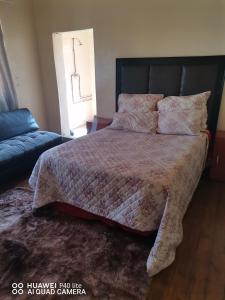 a bedroom with a large bed and a couch at New Dawn Guest House in Brakpan