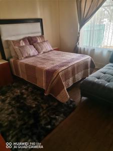 a bedroom with a bed and a window and a couch at New Dawn Guest House in Brakpan