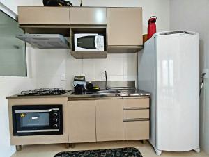 a small kitchen with a refrigerator and a microwave at Apartamento Descubra Palhoça - Pinheira in Palhoça