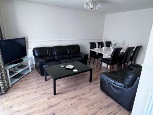 a living room with black leather furniture and a table at 3 Bedroom House with Garden in Buckinghamshire