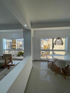 um quarto branco com uma mesa, cadeiras e janelas em Blissapartments T2 - Simone (nearby the beach) em Mindelo