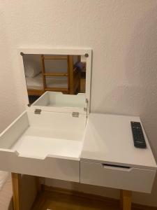 einen weißen Schreibtisch mit einem Spiegel und einer Fernbedienung in der Unterkunft Gasthaus Rössle in Steingrün