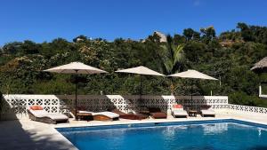 a swimming pool with chairs and umbrellas next to at Cabañas Sicarú Mazunte in Mazunte