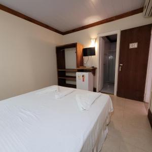 1 dormitorio con 1 cama blanca y TV en Pousada Aquário, en Isla de Boipeba