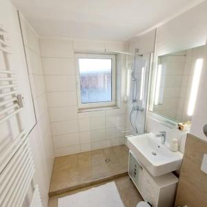 a white bathroom with a sink and a window at Schmidis Ferienwohnung Sonthofen in Sonthofen