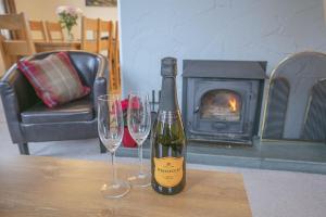 a bottle of wine and two wine glasses on a table at Craigievern Holiday Cottage in Drymen