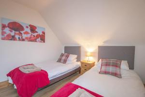 um quarto com duas camas com flores vermelhas na parede em Craigievern Cottage em Drymen