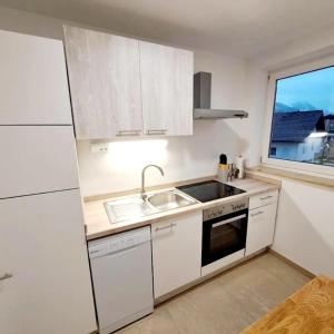 a kitchen with white cabinets and a sink and a window at Schmidis Ferienwohnung Sonthofen in Sonthofen +9 photos