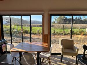 comedor con mesa, sillas y ventanas en Cabaña en sector Aquelarre, Lago Vichuquén, en Vichuquén