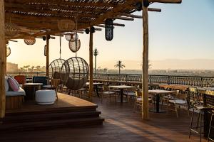 a restaurant with tables and chairs on a deck at Nobu Hotel Marrakech in Marrakech