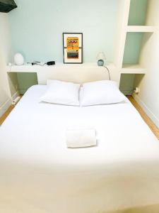 un letto bianco con due cuscini in una stanza di Coeur Feydeau Kervegan le Duplex hyper centre a Nantes