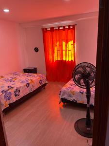a bedroom with two beds and a fan in front of a window at Casa Vecchio in Cartagena de Indias