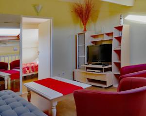 uma sala de estar com televisão e cadeiras vermelhas em Lodge Mendia em Anglet