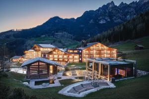 una gran casa en una colina con montañas en el fondo en Cyprianerhof Dolomit Resort en Tires